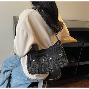Détail du sac bandoulière en denim délavé avec clous en métal argenté et multiples poches
