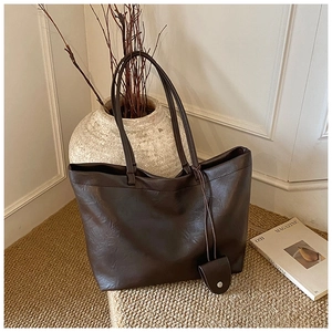Close-up of deep brown leather tote bag texture and hanging coin pouch detail