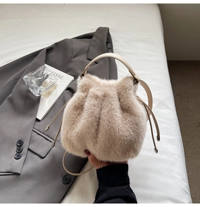 Close-up of beige plush faux fur bucket bag with leather handles and drawstring closure