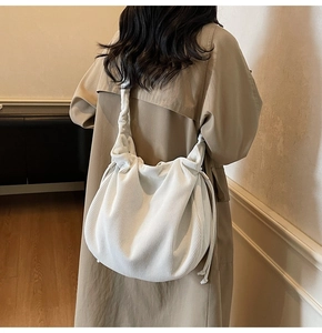 Detail der weißen Cord-Hobo-Tasche mit Kordelzug-Falten, am Modell in warmem Interieur