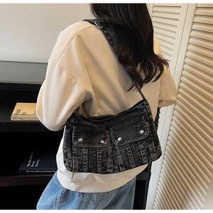 Close-up of vintage washed denim crossbody bag with dual utility pockets and metal buckles