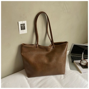 Close-up of brown PU leather tote bag with soft pebble texture and thin shoulder straps