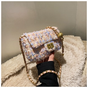 Detailed macro view of the colorful tweed fabric and golden ball chain strap on the mini bag