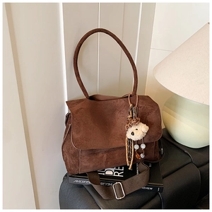Close-up of brown suede tote bag featuring a plush bear charm and leopard print ribbon
