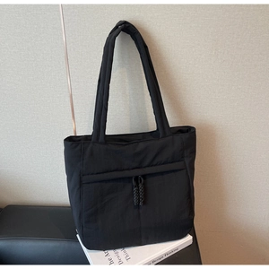 Detail einer schwarzen gesteppten Nylon-Einkaufstasche mit Kordelzug auf Büchern