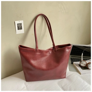 Macro view of burgundy PU leather tote bag with subtle texture and long handles