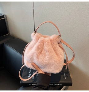 Close-up of pink faux fur bucket bag with leather handles and drawstring closure