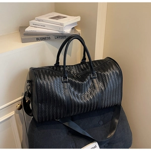 Détail du sac de voyage tissé noir avec texture mate et bandoulière amovible