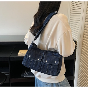Vue détaillée d'un sac à épaule en denim bleu foncé avec poches cargo et clous argentés