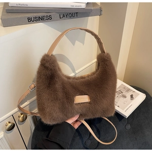Detail of the brown plush tote bag featuring a leather label and adjustable shoulder strap
