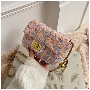 Detail of tweed crossbody bag with gold turn-lock and woven chain strap in hand