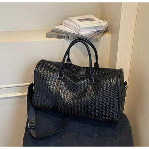 Vue détaillée de la texture tissée en V noire d'un grand sac de voyage élégant