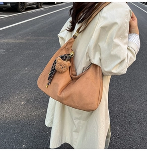 Dettaglio ravvicinato della borsa hobo in camoscio marrone con ciondolo a forma di orso