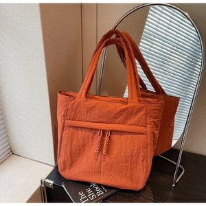 Detailaufnahme der orangefarbenen Tragetasche aus Nylon mit Quasten-Details