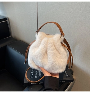 Detail of plush faux fur bucket bag with brown leather handle and drawstring closure