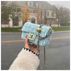 Close-up of light blue tweed crossbody bag with gold chain strap and metal ball detail