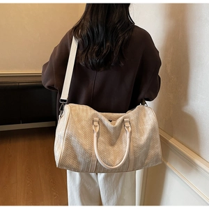 Détail du sac de voyage en cuir tressé crème avec large bandoulière porté par un mannequin