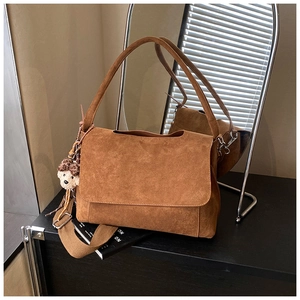 Detail of caramel suede shoulder bag with dual straps and cute plush bear charm