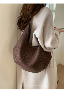 Detail of a large brown leopard print hobo bag worn with a beige wool coat