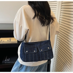 Détail du sac en denim bleu foncé avec doubles poches à rabat et coutures blanches