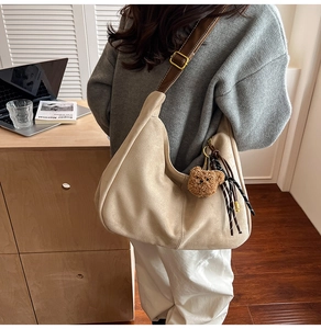 Dettaglio borsa tote beige in scamosciato con tracolla marrone e ciondolo orsetto morbido