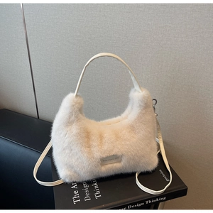 Detail of creamy faux fur handbag with love every day patch on a black book
