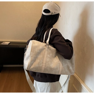 Détail d'un sac de voyage tressé crème avec texture fine et bandoulière réglable