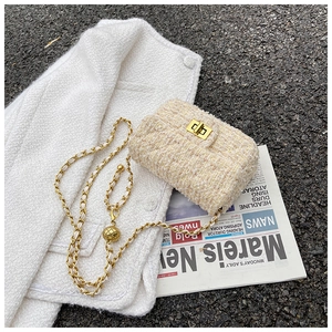 Detail of beige tweed crossbody bag with gold chain strap and metal rotary lock clasp