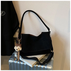 Black suede tote bag detail with wide strap and cute brown plush bear charm