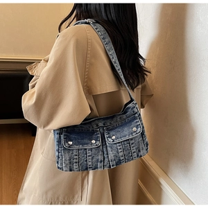Gros plan d'un sac à bandoulière en denim bleu avec des poches sur un trench-coat kaki