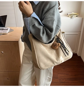 Dettaglio della grande borsa tote in pelle scamosciata beige con ciondolo a orsetto