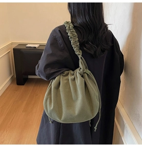 Detail der grünen Cord-Kordelzug-Schultertasche mit Faltenhenkel auf einem Rücken