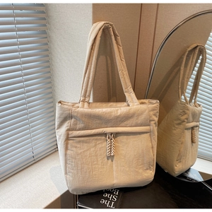 Detailansicht der beigefarbenen Stepptasche mit geflochtenen Seilanhängern im Innenraum