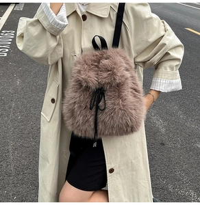 Chic taupe faux fur backpack with black drawstring closure shown on a beige trench coat