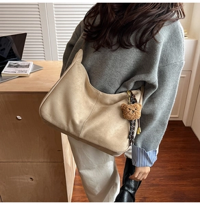 Vista dettagliata della borsa tote in pelle scamosciata beige con ciondolo a orsetto