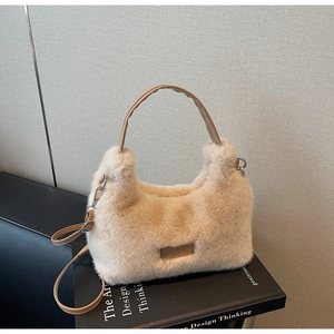 Close-up of plush faux fur handbag in cream with leather handles on a book