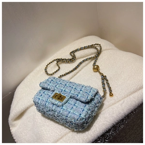 Macro shot of light blue tweed mini bag featuring gold chain strap and metal ball detail