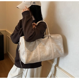Détail du sac de voyage tressé crème avec bandoulière porté par un mannequin