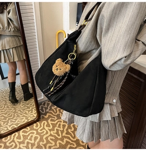 Dettaglio borsa hobo nera opaca con fibbia dorata e portachiavi a forma di orsetto