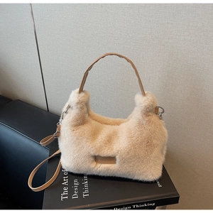 Detail of plush beige crossbody bag featuring leather handles on a black art book