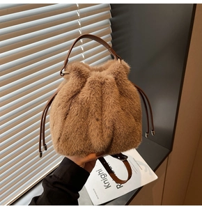 Detail view of brown plush bucket bag with leather drawstring and elegant gold hardware