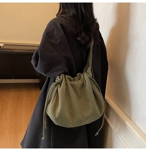 Schultertasche aus olivgrünem Kord mit Kordelzug und Falten am Modell getragen