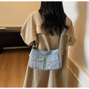 Détail d'un sac bandoulière en denim délavé avec deux poches cargo sur un manteau kaki
