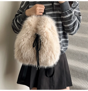 Close-up of a plush beige faux fur drawstring backpack with black cords on a model
