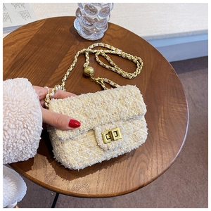 Detail of tweed crossbody bag with golden chain strap and round ball adjustment charm