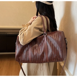 Sac de voyage tressé marron foncé porté à l'épaule pour une vue réelle de sa taille