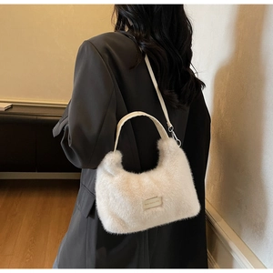 Detail of white faux fur crescent bag with love every day tag and leather handle