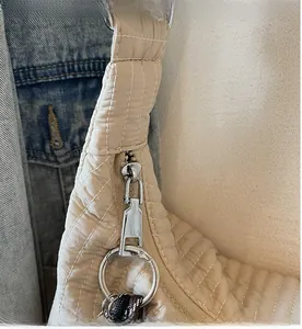 Detailed close-up of smooth silver zipper and quilted beige nylon fabric on the tote bag
