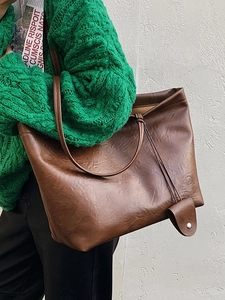 Minimalist brown leather tote bag with slim shoulder straps and vintage texture in usage