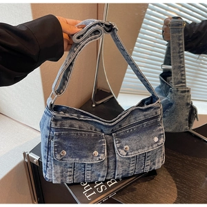 Gros plan sur un sac bandoulière en denim bleu délavé avec poches cargo et boucles argentées